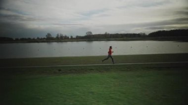 Almanya 'da parkta göl boyunca koşan bir adam. Atletik genç insan doğada koşar. Sağlıklı bir yaşam tarzı. Erkek, Münih 'teki bir şehir parkında gölet kenarında koşuyor. Göl kenarındaki patikada koşan adam.. 