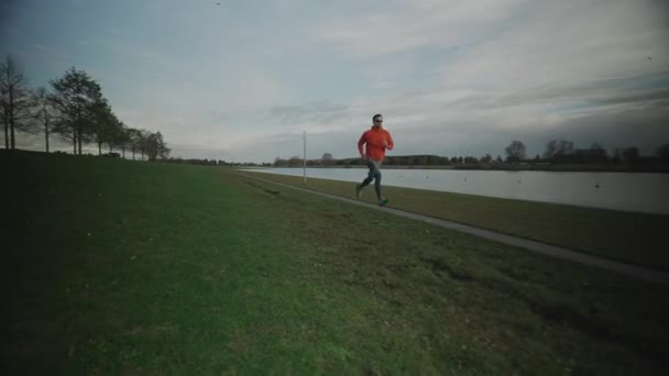 秋にはドイツ ミュンヘン ドイツの公園の湖沿いの歩道に沿ってジョギングスポーツマン 男性は秋に池のそばを走る 水による屋外運動 人とスポーツの概念 — ストック動画