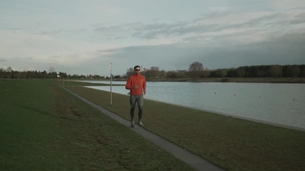 德国慕尼黑 一名男子沿着湖边的小径慢跑 秋天的时候 男人在池塘边奔跑 在水边进行户外活动 人与体育概念 — 图库视频影像