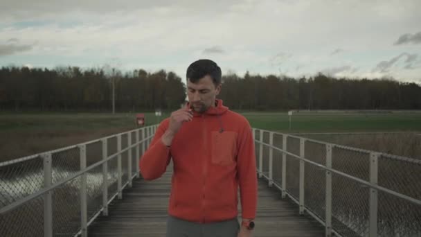Běží Hudbou Muž Před Začátkem Venkovního Joggingu Podzim Nasadí Uší — Stock video