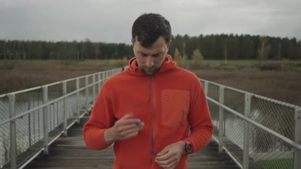 Male Runner Puts Channel Wired Headphones His Outdoor Running Workout — Stock Video