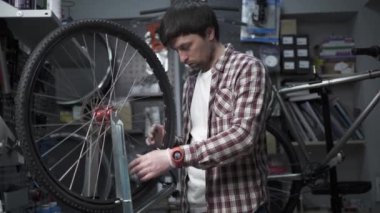 Bisiklet atölyesinde tekerlek düzelticisi. Tamirci Velocipede 'in kenarındaki telleri germek için alet kullanır. Küçük işletme bisikleti tamiri ve servis teması. Dönme dolap. Döngüsel mekanik tekerleği tamir eder. 