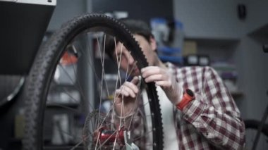 Bisiklet atölyesinde tekerlek düzelticisi. Tamirci Velocipede 'in kenarındaki telleri germek için alet kullanır. Küçük işletme bisikleti tamiri ve servis teması. Dönme dolap. Döngüsel mekanik tekerleği tamir eder 