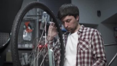 Atölyede bisiklet tamiri. Erkek motor tamircisi tekerleği tamir eder, tekerlekleri ayarlamak için özel aletleri olan gerilim telleri. Tamirci bisiklet servis istasyonunda çalışarak tekerlek tellerini tamir ediyor.. 