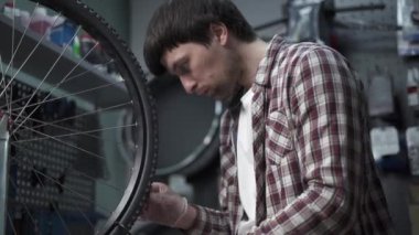 Bisiklet tamirhanesinde jant ve tekerlek direksiyonlarının hizalanması. Tekerlek tellerini sıkma atölyesinde özel aletleri olan bir tamirci. Döngüsel mekanik tekerleği tamir eder. 