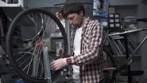 车轮矫直站在自行车车间 机修工使用工具来拉紧速度踏板边缘的勺子 小商业自行车修理和服务主题 真正的自行车轮 自行车修理工修理轮 — 图库视频影像