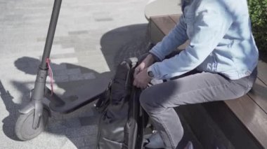 Orta yaşlı serbest çalışan kadın ofis binasının yanındaki parkta otururken sırt çantasından laptop alıyor. Yaşlı bir kadın çantasından bilgisayarını çıkardı ve elektrikli scooterla geldi. Aktif kıdemli kadın uzak iş