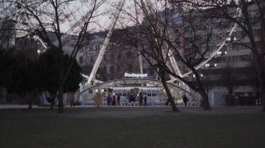 Budapeşte, Macaristan 'da alacakaranlıkta dönme dolap. Elisabeth meydanının alacakaranlıktaki aydınlanmış dönme dolap manzarası. Eğlence parkı kavramı, adil, heyecan verici. Macaristan 'ın başkentine turist gezisi. 