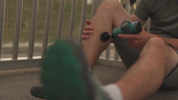 Sportler Wärmt Muskeln Bein Mit Einem Prallmassager Auf Dem Outdoor — Stockvideo