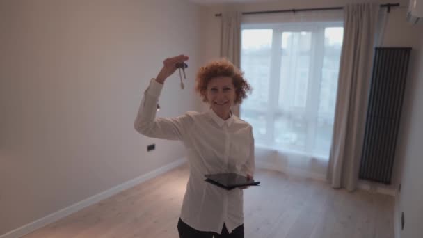妇女房地产经纪人站在空房子里 手里拿着钥匙 卖房产的女人专业的房地产经纪人出售和租赁公寓的概念 提供地产的地产经纪 — 图库视频影像
