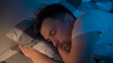 Genç bir adam gece yatağında uyanır ve yorgun bir bakışla gözlerini ovuşturur ve yastığın altından akıllı telefonu çıkarır. Erkek uyuya kalamaz ve telefonda zamanı kontrol edemez. Uyku problemleri, alet bağımlılığı 
