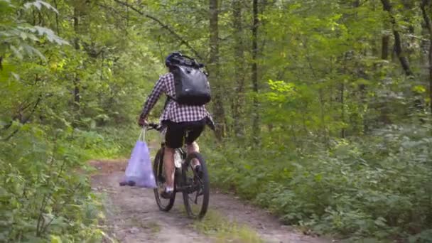 汚染だ 生態学的問題 男性サイクリストは汚染を除去した後 ハンドルバー自転車にゴミ袋を運びます 男性はエコマラソンやペットボトルの清掃などのゴミ収集を行います — ストック動画