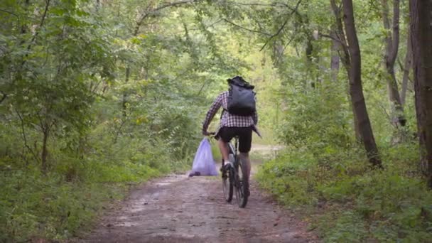 生态问题 在清除污染后 骑自行车的男性骑自行车的人把垃圾袋放在车把上 男子在生态马拉松 清洗塑料瓶和其他垃圾的过程中收集垃圾 — 图库视频影像