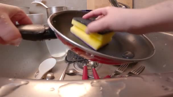 女性の手は台所の流しで鍋を洗う 手で手動洗浄し 手動で台所用品 食器洗い機はありません 主婦は台所のシンクで洗剤とスポンジでフライパンをきれいにします — ストック動画