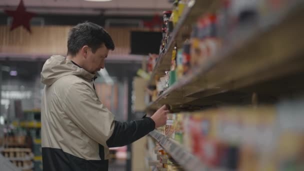 Сосредоточенный Молодой Человек Читает Этикетки Продуктах Супермаркете Внимательно Изучает Ингредиенты — стоковое видео