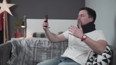 Genç adam evinde oturup video konuşmalarında boynunu nasıl yaraladığını ve şimdi rehabilitasyona ihtiyacı olduğunu ve boyunluk takması gerektiğini anlatıyor. Boyun korsesi. Omurga travması.. 