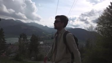 Almanya 'da doğa yürüyüşü ve seyahat teması. Erkek yürüyüşçü, Deuchland 'daki Schliersee Gölü yakınlarındaki bir orman yolunda dağlarda yürüyor. Tepelerde tek günlük geziler. Hafta sonu yürüyüş gezisi. 