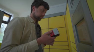 Adam paket göndermek için sarı paket istasyonunu kullanıyor. Alman paket servis terminali. Deutschland 'daki sarı paketleme merkezine gönderen tip etiketi ve paket gönder. 