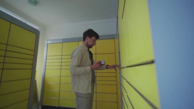 Paketi bırakmak için otomatik teslimat terminalini kullanan bir erkek müşteri. Posta otomatik paket alma noktası adamı işletim ekranında telefon ve kutu tutuyor.. 