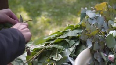 Personel etkinliği ajansı iş başında. Çiçekçiler biner, çiçekleri düğün töreni için kemerle süslerler. Profesyonelce düğün dekorasyonu yaratmak. Çiçekçilik. Düğün kemeri için çiçek kompozisyonuyla çalışan bir dekoratör