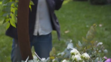 Profesyonel çiçekçi iş başında. Genç ve güzel bir kadın modern yeşil buketi farklı renklerde yapıyor. Çiçekli düğün kemeri tasarımı. İş konsepti. Sonbaharda dışarıda çalışan bir dekoratör..