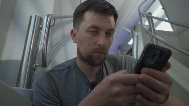フライヤーとサーフィンインターネット上に座っているデュアルデッキ電車の中で男性通勤 ヨーロッパでは夏に空の座席がないので 男は階段に座っている間に2階建ての鉄道列車に乗ります — ストック動画