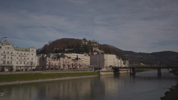 ザルツブルク オーストリア 晴れた冬の日にザルツブルクの川の上のシティスケープ サルジャ リバーフロント ザルツブルクの旧市街 オーストリア ヨーロッパのサルヴァッツ川の銀行 タウンビュー — ストック動画