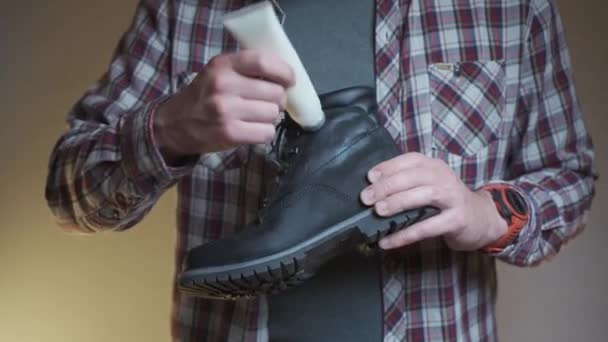 男性は保護のために冬のブーツに保護油を適用します 男性は特別なクリームと黒い着色された靴を潤滑します 特別に配合された脂肪による靴の保護とクリーニング — ストック動画