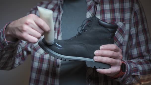 人在冬靴上涂上保护油以保护自己 男性用特殊的奶油润滑黑色的鞋子 用特别配制的脂肪保护和清洗鞋子 — 图库视频影像