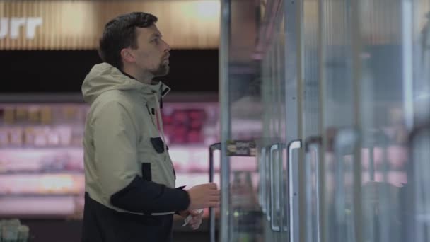 Jovem Escolhe Comida Frigorífico Supermercado Compra Refeições Pré Fabricadas Congeladas — Vídeo de Stock