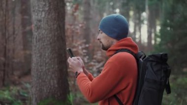 Yürüyüş yaparken açık hava haritaları. Yürüyüşçü, uygulama haritalama yoluyla ormanda yön bulmak için akıllı telefon kullanır. Akıllı telefondan güzergahlar çiziyor. Gezgin GPS kullanarak ormanda yolunu bulur. Keşfedin ve yürüyün. 