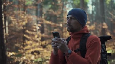 Yürüyüş yaparken açık hava haritaları. Yürüyüşçü, uygulama haritalama yoluyla ormanda yön bulmak için akıllı telefon kullanır. Akıllı telefondan güzergahlar çiziyor. Gezgin GPS kullanarak ormanda yolunu bulur. Keşfedin ve yürüyün. 