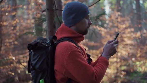 徒步旅行者在秋天野外远足时使用智能手机在树林中导航 旅行者在穿越森林的过程中 通过电话使用Gps导航应用程序 地理定位系统 — 图库视频影像