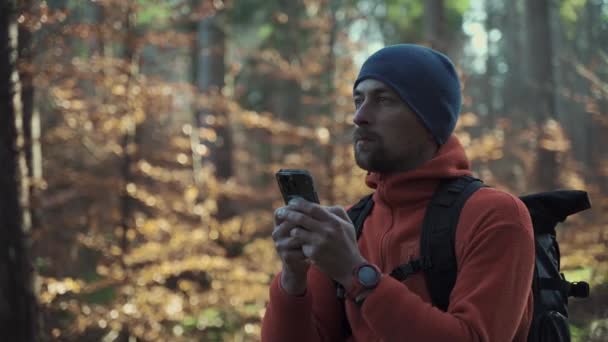 ハイキング中に屋外でマップします ハイカーはスマートフォンを使ってアプリの地図作成で森の中をナビゲーションします スマートフォンでルートをトレッキング 旅行者はGpsを使用して森の中をナビゲートします 探検とハイキング — ストック動画