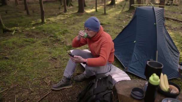 Утром Кемпинге Осеннем Лесу Турсит Просматривает Интернет Своем Смартфоне Сидя — стоковое видео