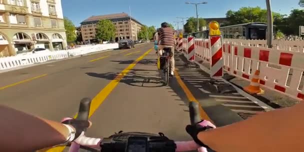ミュンヘン ドイツのサイクルウェイのフェンスでリノベーションのために閉鎖しながら 女性自転車の個人的な視点の手 都市ライディング中にピンクのリボンが付いたPovサイクルハンドルバー — ストック動画