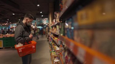 Markette alışveriş yapan, alışveriş sepetiyle yürüyen, süpermarkette karantina sırasında gerekli malzemeleri alan, koruyucu maske takan bir adam. Yeni normal, covid 19 ve alışverişler. Maske yoksa giriş de yok.