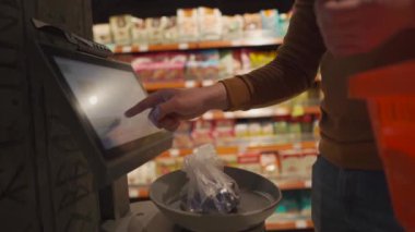 Maskeli adam, karantina sırasında süpermarkette bir şeyi tartıp barkodluyor. self-servis, markette alışveriş yemekleri, sosyal mesafeler ve karantina koronavirüsü. Piyasada şekerleri tartmak.