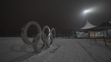 Olimpiyat oyunları, Münih, Almanya 'da Olimpiyat Parkı' nda karlı bir akşamda logoda. Olympia Muenchen 'deki bir parkta karların içinde yüzüyor. Olympiapark Münih. Olimpiyat Çemberi. 