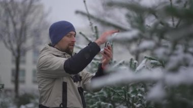 Video vlogger akıllı telefonuyla sosyal medya platformları ve takipçileri için seçtiği Noel ağacını internetten kışın karlı havalarda sokak İsa 'nın doğumu pazarında görüntüler kaydediyor.. 