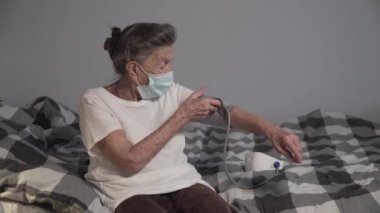 Bakıcı, Covid 19 salgını sırasında evde bulunan yaşlı bir kadının tansiyon ölçümünü kontrol ediyor, yaşlılar sağlığını kontrol ediyor, kan basıncı monitörü kullanıyor, sağlık hizmeti veriyor, evde kalıyor. Tıbbi kontrol.