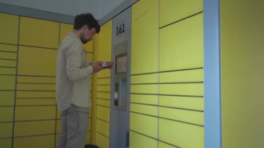 Adam paket göndermek için sarı paket istasyonunu kullanıyor. Alman paket servis terminali. Deutschland 'daki sarı paketleme merkezine gönderen tip etiketi ve paket gönder. 