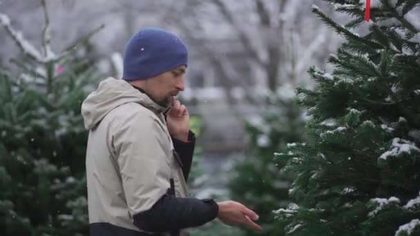 Hombre Selecciona Árbol Navidad Mercado Navideño Toma Consejos Sobre Elección — Vídeos de Stock