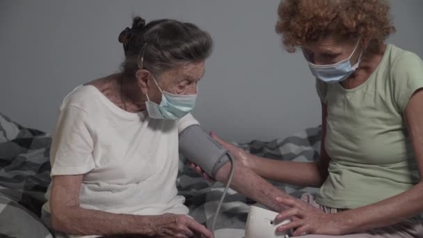 Зрелая Женщина Сиделка Медицинской Маске Проверяет Кровяное Давление Пожилых Пациентов — стоковое видео