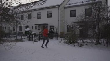 Adam şehirde parkta karlı yolda koşuyor Almanya 'da kışın kulaklıkla müzik dinliyor. Dondurucu soğukta kulaklık takan sporcu. Kışın karda koşmak. 