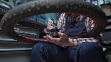 Bisiklet tamirhanesinde bisiklet tekerleğini tamir eden erkek bisikletçi. Arka gövde yatakları değiştiriliyor. Bisiklet bilyelerinin ve kayganlaştırıcının yeniden toplanması. Bisiklet tamircisi çalışıyor. Atölyedeki teknisyen. 