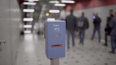 Münih, Almanya 'da metroda arka planda yürüyen yolcular için mavi renkli toplu taşıma bileti onaylayıcısı. Munchen, Deuschland 'daki metro istasyonunda toplu taşıma bilet damgası makinesi.. 