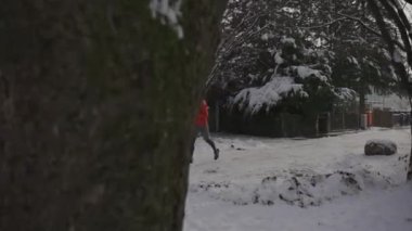 Orman parkında erkek koşucunun müzik dinleyerek antrenman yaptığı kış koşusu. Sporcu soğuk havada dışarıda antrenman yapıyor. Kışın karlı havada spor kıyafetleri ve kulaklık takıyor.