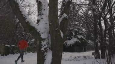 Erkek koşucu kışın turuncu eşofman altı arka görüşüyle karda koşuyor. İnsanlar günlük açık hava yaşam tarzları. Sporun tadını çıkarıyorum. Kış mevsiminde koşan insan izlerinin dikiz aynasından. Dondurucu karlı havada koş. 