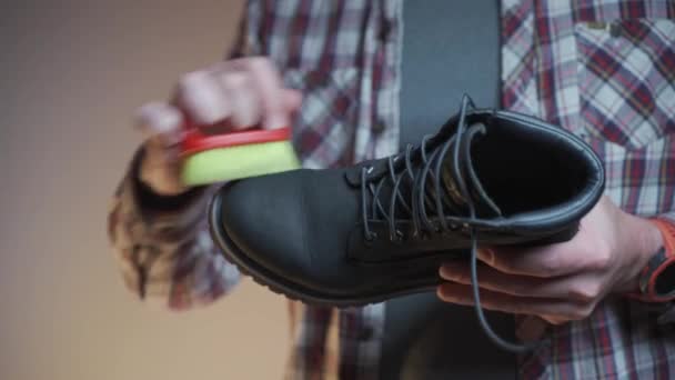 プロの靴のケアとクリーニング会社 潤滑剤を適用する前に男は黒スエード冬のブーツから汚れやほこりをブラシ 履物のメンテナンスのための付属品 慎重な労働者は冬の靴をきれいに — ストック動画